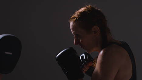 Close-Up-Studio-Shot-Of-Two-Mature-Women-Wearing-Gym-Fitness-Clothing-Exercising-Boxing-And-Sparring-Together-1